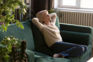 A woman relaxing on a couch with a plant nearby.